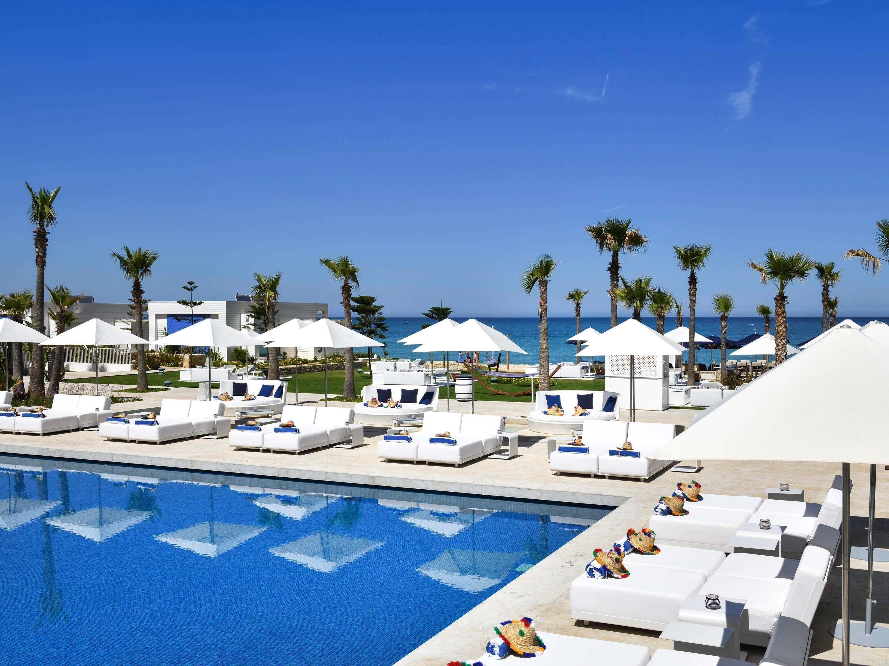 Alberca techada, alberca al aire libre y sombrillas en la alberca