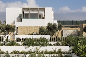 A modern two-story building with a white facade, stone accents, and a balcony with blue cushions. - Sofitel Tamuda Bay Beach and Spa (M'diq)