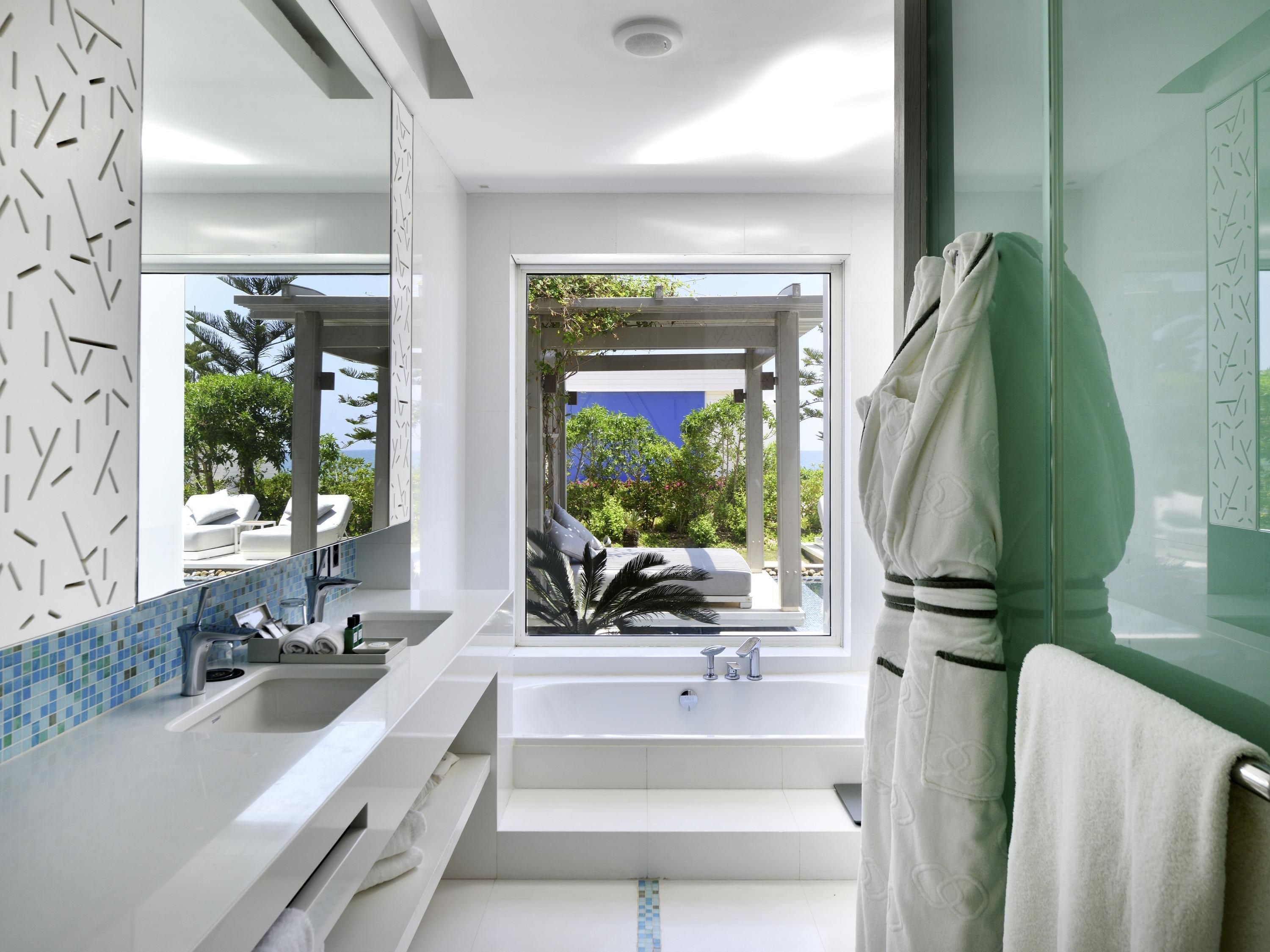 Un baño moderno con un ventanal grande, una bañera y zona de ducha.