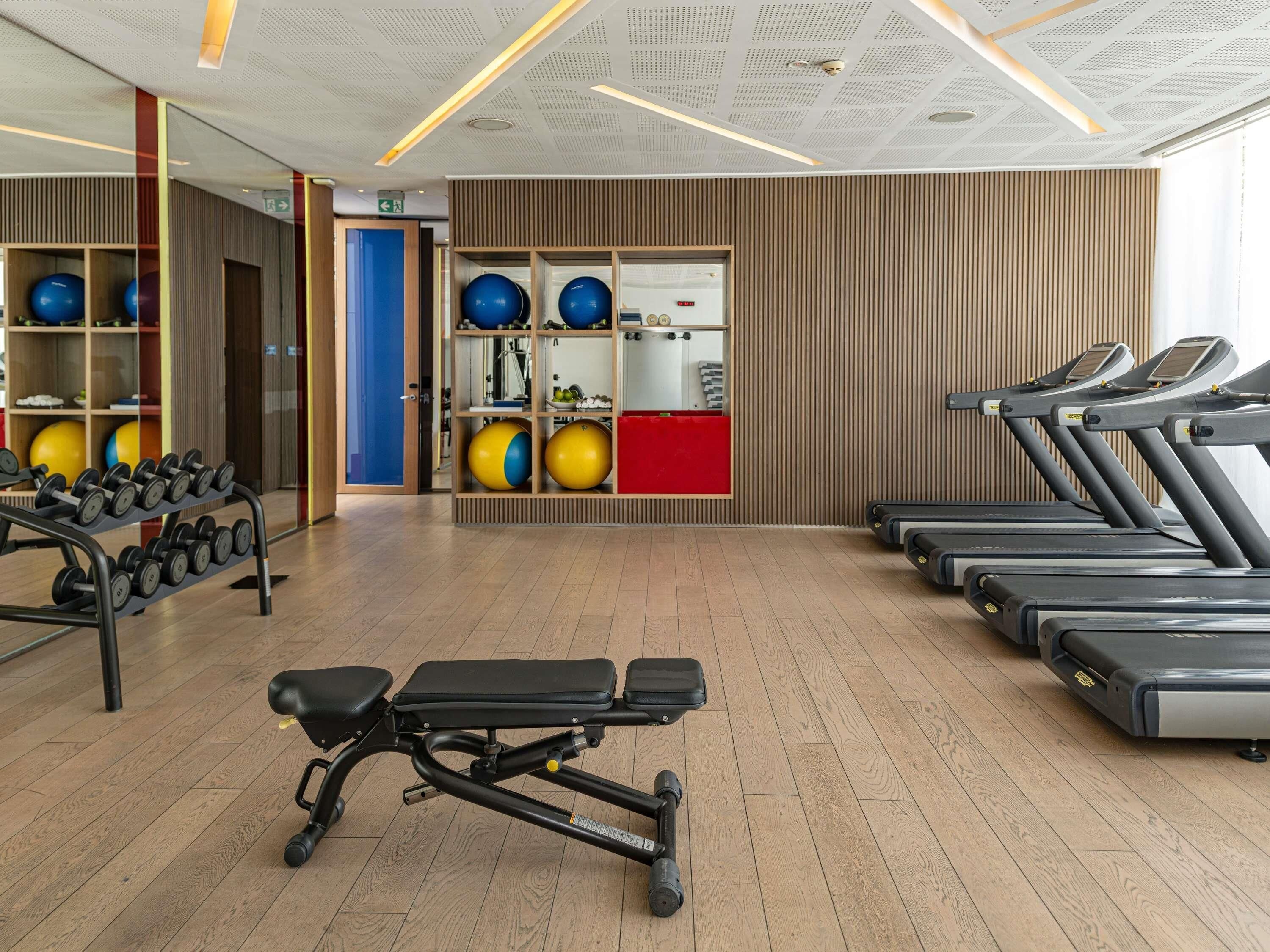 Une salle de sport équipée de tapis de course, d’haltères et de ballons d’exercice.