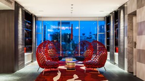 A modern interior with two red woven chairs, a multicolored striped table, and a red and white rug. - Sofitel Tamuda Bay Beach and Spa (M'diq)