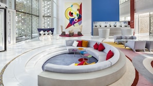 A modern lobby with a central seating area, a reception desk, and a large abstract painting. - Sofitel Tamuda Bay Beach and Spa (M'diq)