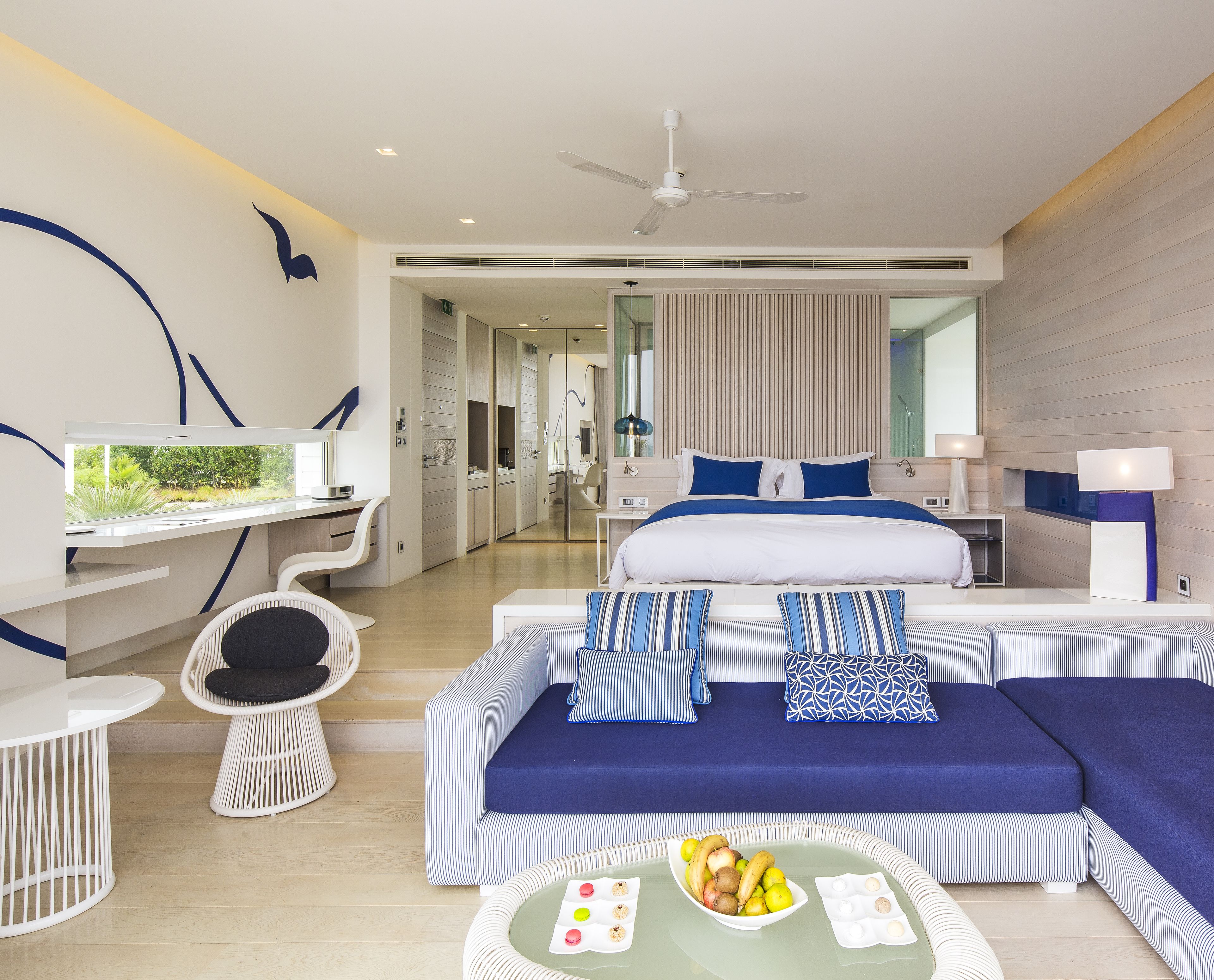 Una habitación de hotel moderna con una cama grande, un escritorio, una silla y una mesa de comedor.