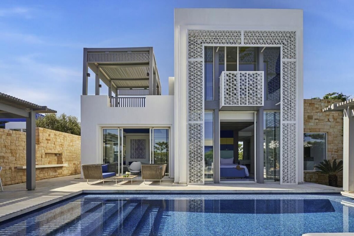 A modern two-story house with a swimming pool, large glass doors, and a balcony.