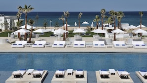 A resort pool area with sun loungers and umbrellas, a clear view of the ocean, and a well-maintained lawn. - Sofitel Tamuda Bay Beach and Spa (M'diq)
