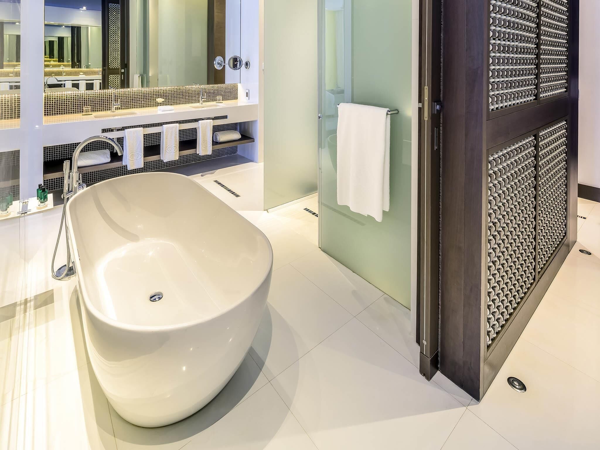 A modern bathroom with a freestanding bathtub, a glass shower enclosure, and a decorative wall panel.