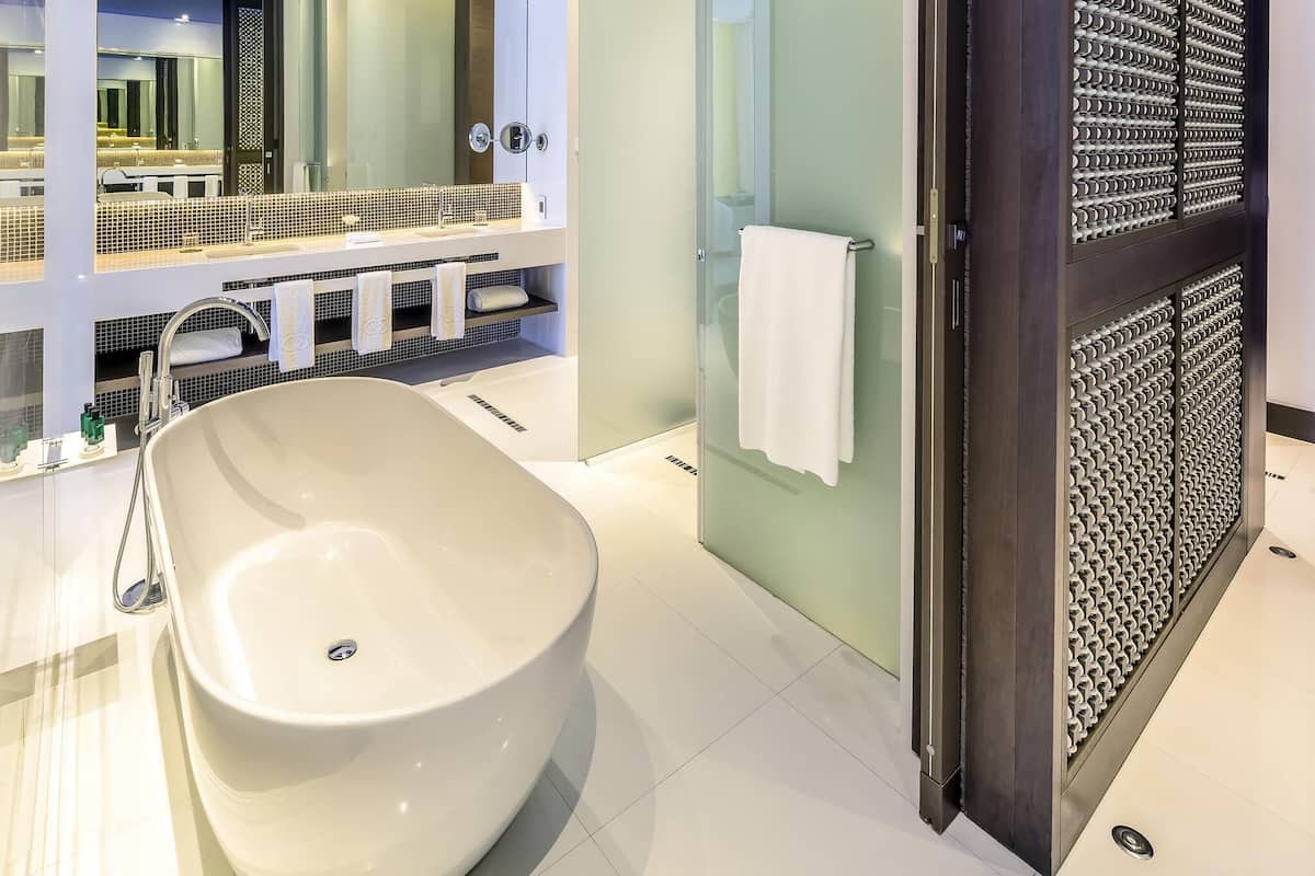 A modern bathroom with a freestanding bathtub, a glass shower enclosure, and a decorative wall panel.