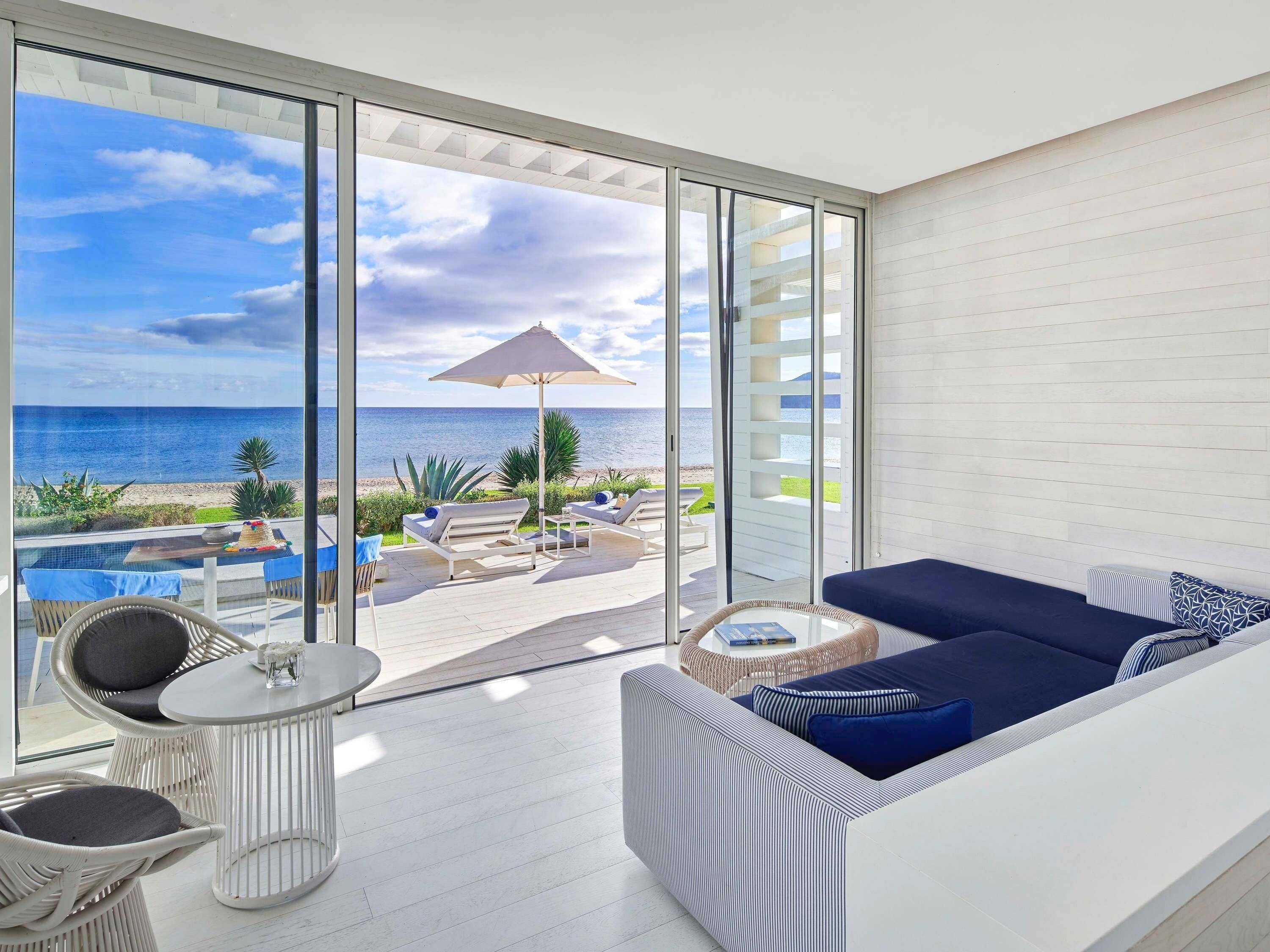 Un balcón con vista al mar, un sofá, una mesa y sillas.