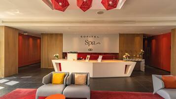 Un moderno vestíbulo de hotel con mostrador de recepción, sofás y una alfombra roja.