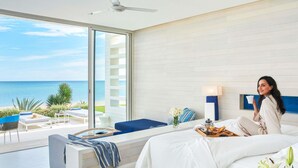 Habitación de hotel moderna con una cama grande, zona de estar y vistas al mar, además de un balcón.