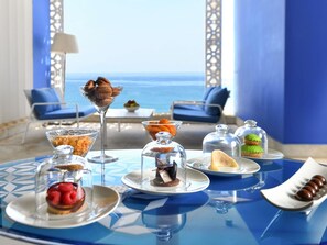 Una mesa servida con diversos postres y vista al mar.