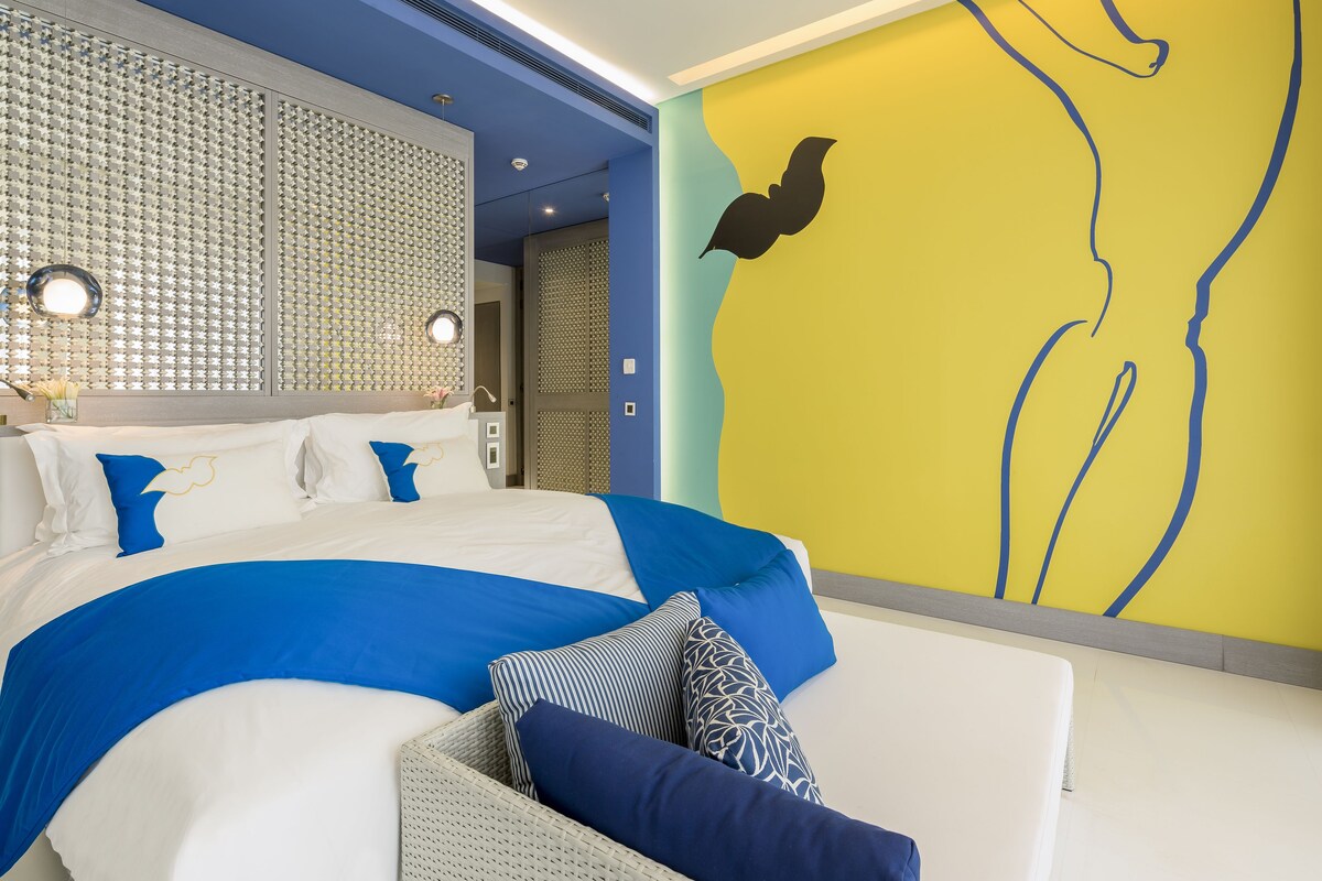 A modern bedroom with a large bed, a decorative wall, and a unique yellow wall design.