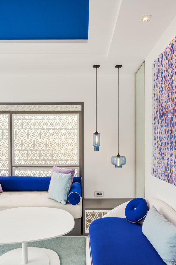 Una sala moderna con un sofá azul, una mesa redonda blanca y una pared con diseño.