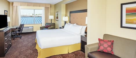 A hotel room with a bed, a desk, a chair, a sofa, and a television.