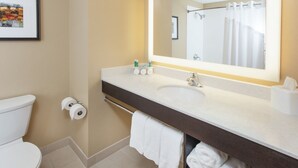 Une salle de bain comprenant des toilettes, un lavabo avec un miroir et un porte-serviettes.