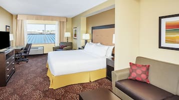 A hotel room with a bed, a sofa, a desk, and a TV.