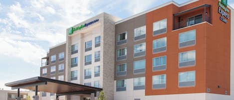 Ein Hotel Holiday Inn Express & Suites mit modernem Design, inklusive überdachter Eingang und Parkplatz.