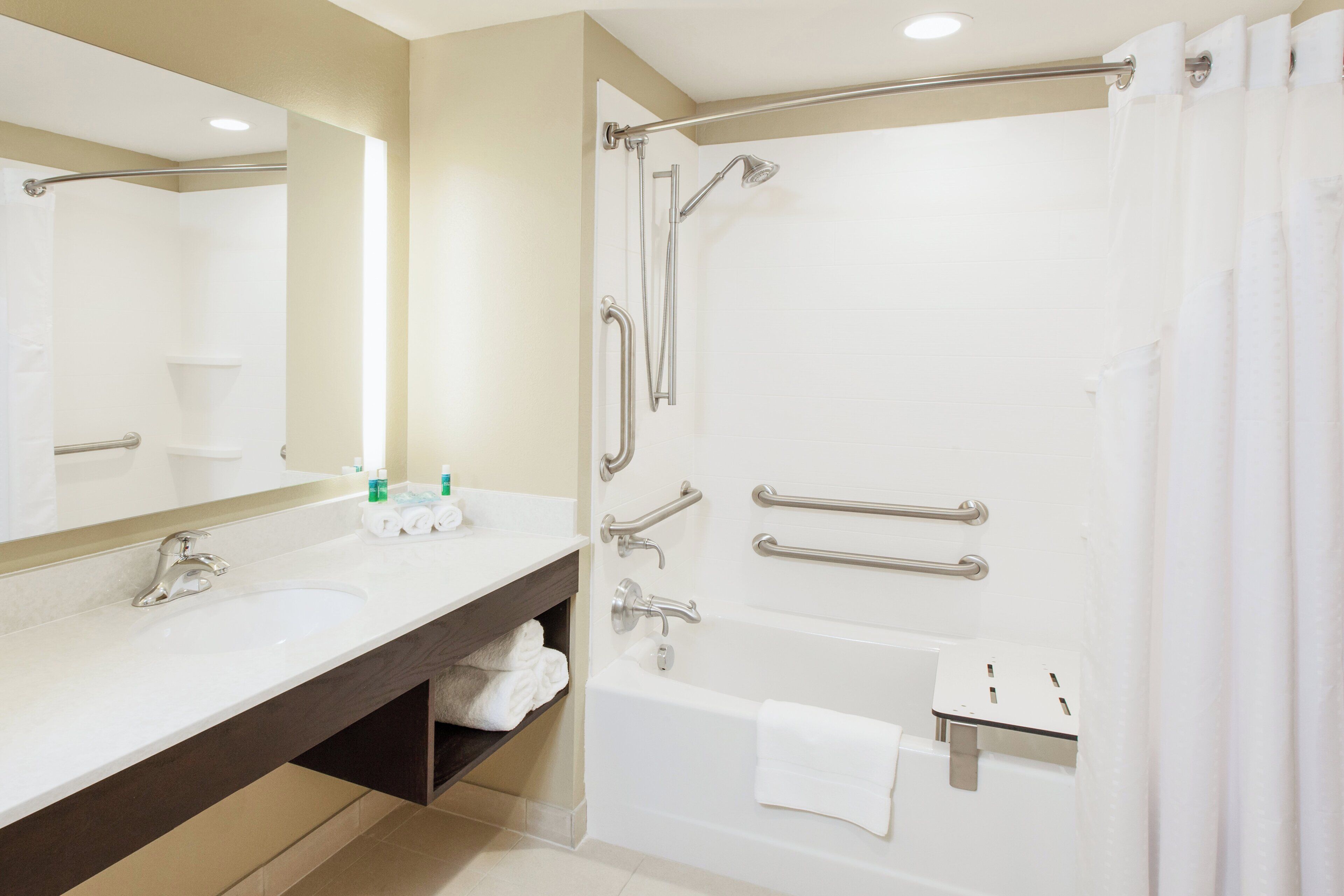 A modern bathroom with a bathtub, a shower, a vanity with a mirror, and a towel rack.