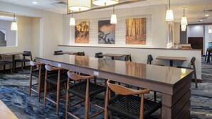 A modern hotel lobby with a long reception desk, bar seating, and artwork on the walls. - Fairfield Inn & Suites by Marriott Santa Cruz, CA (Santa Cruz)