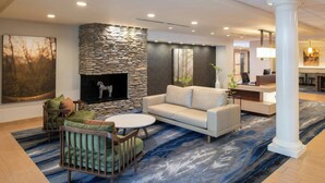 A modern lobby with a stone fireplace, a sofa, a round table, and a reception desk. - Fairfield Inn & Suites by Marriott Santa Cruz, CA (Santa Cruz)
