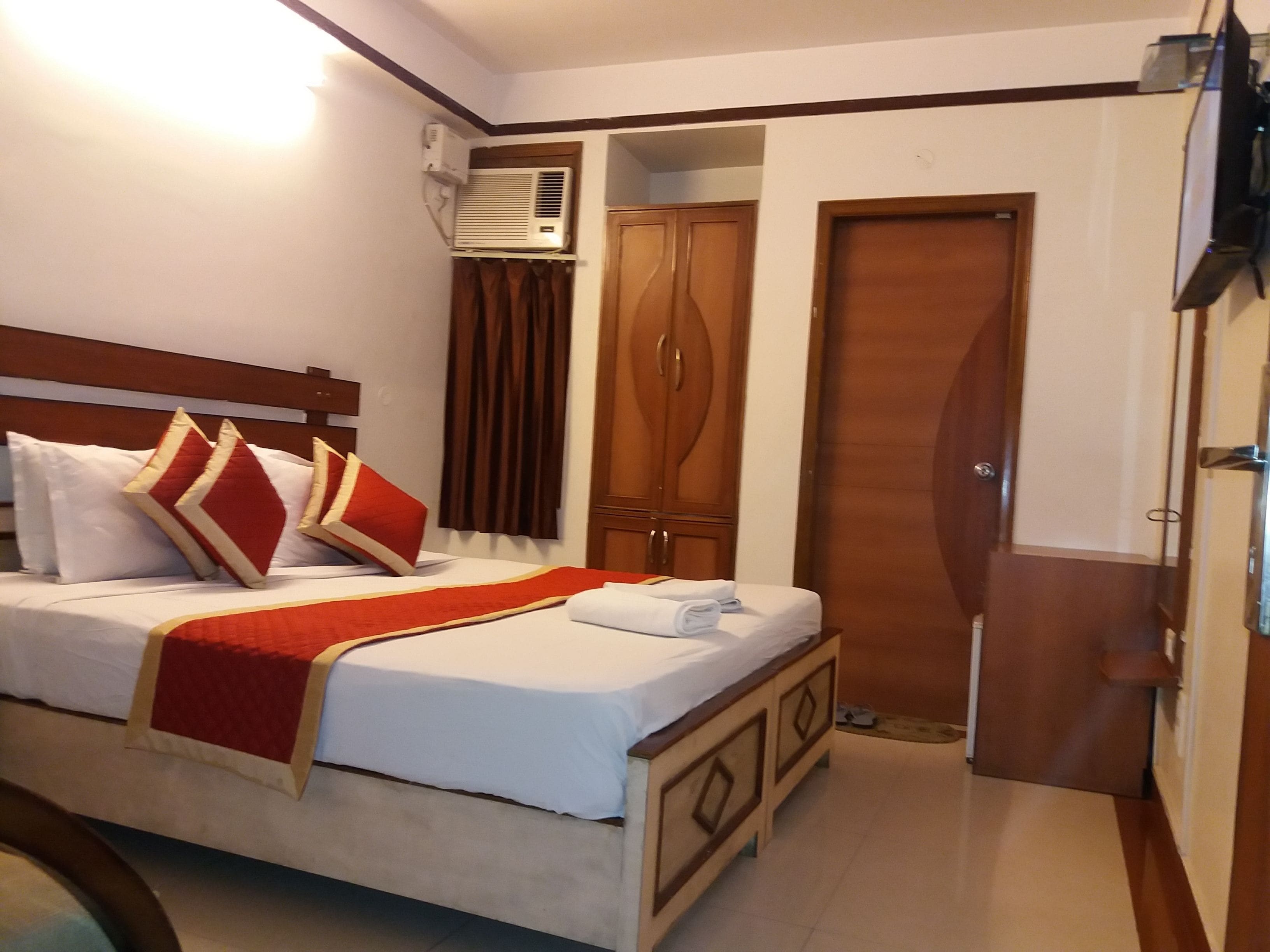 A hotel room with a bed, a wardrobe, and an air conditioning unit.