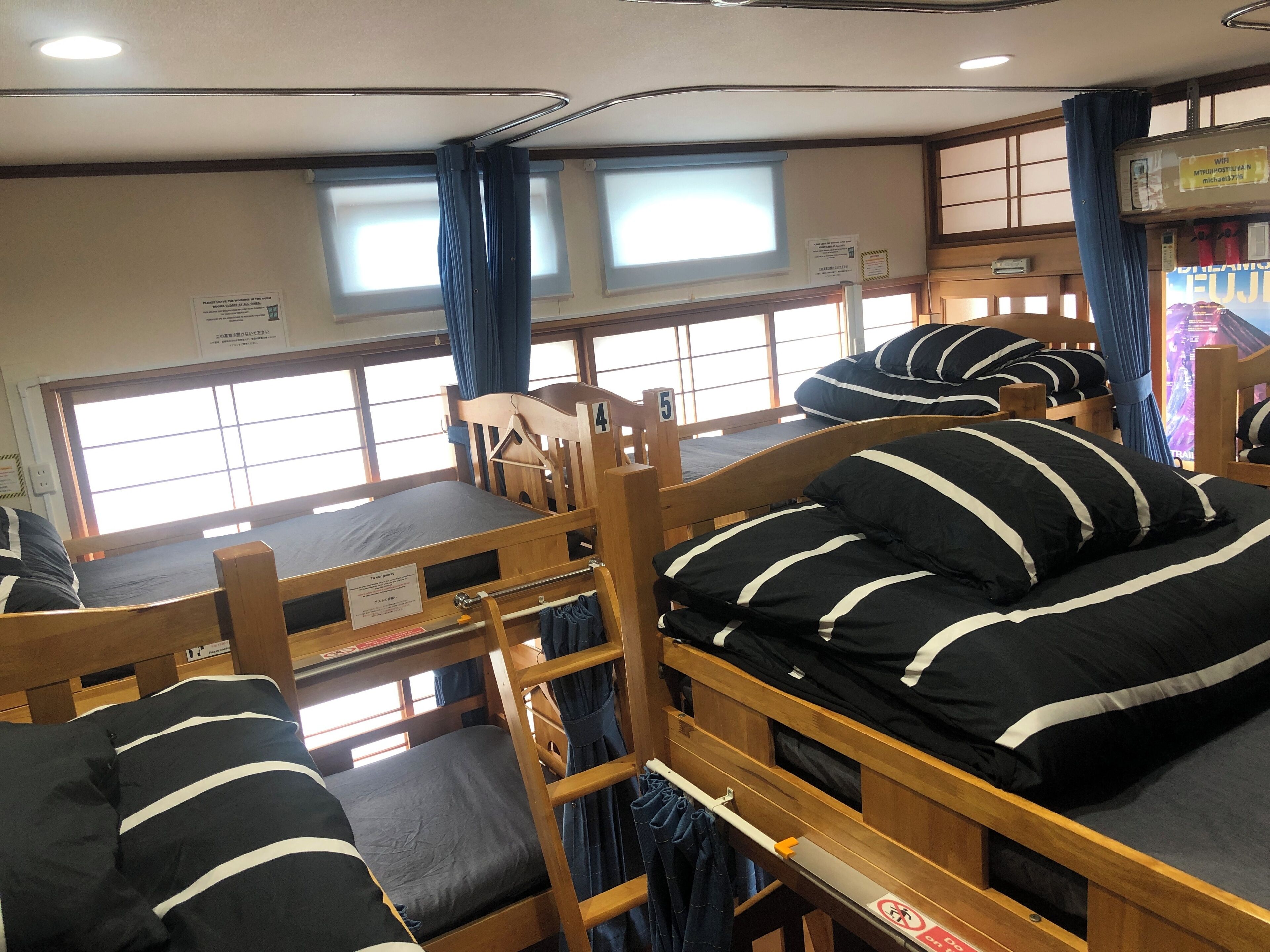 A dormitory room with bunk beds, a window, and a curtain.