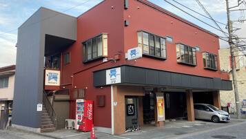 A red building with a sign for 'Mt. Fuji Hostel' and a Coca-Cola vending machine.