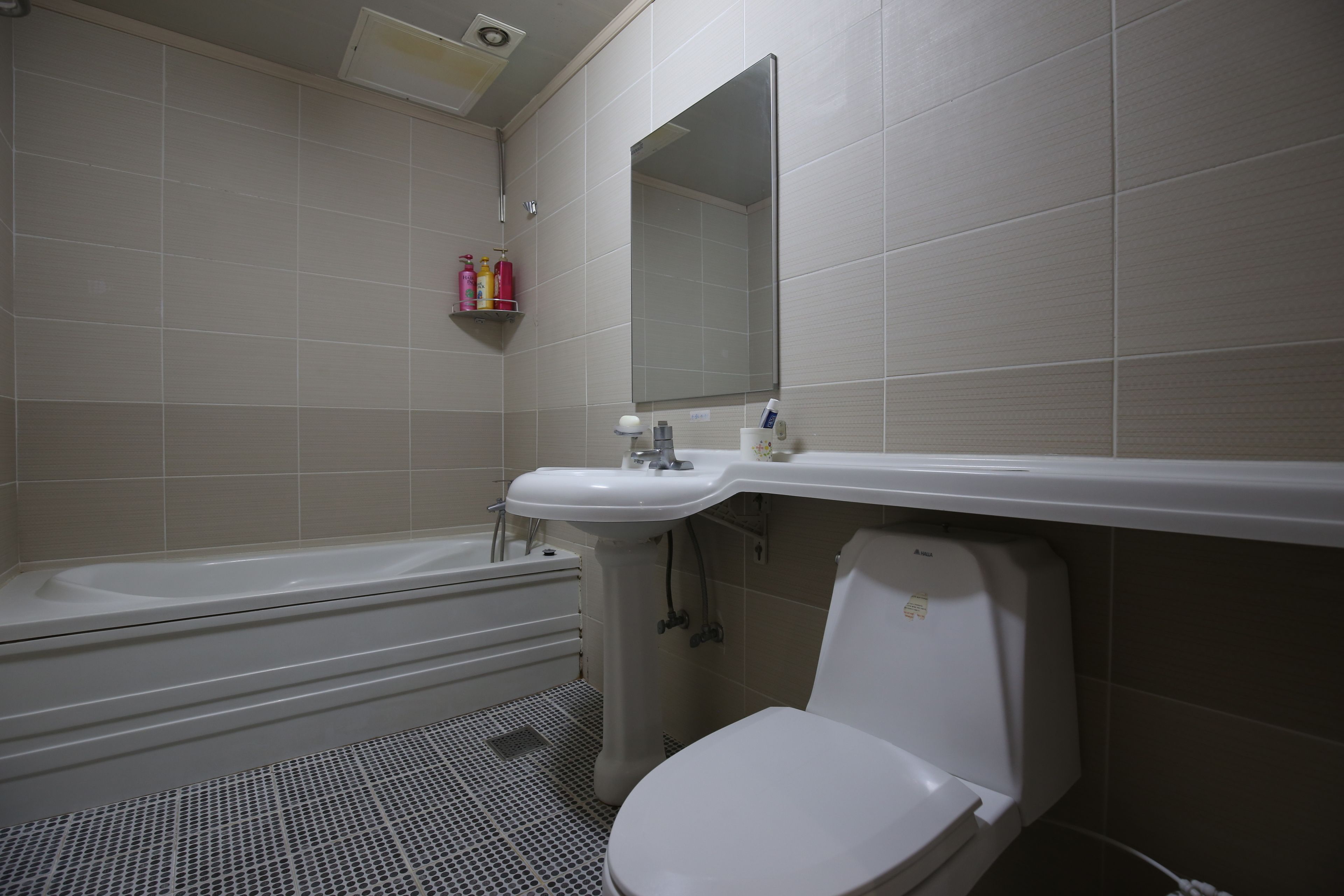 Un baño con bañera, lavamanos, inodoro y espejo.
