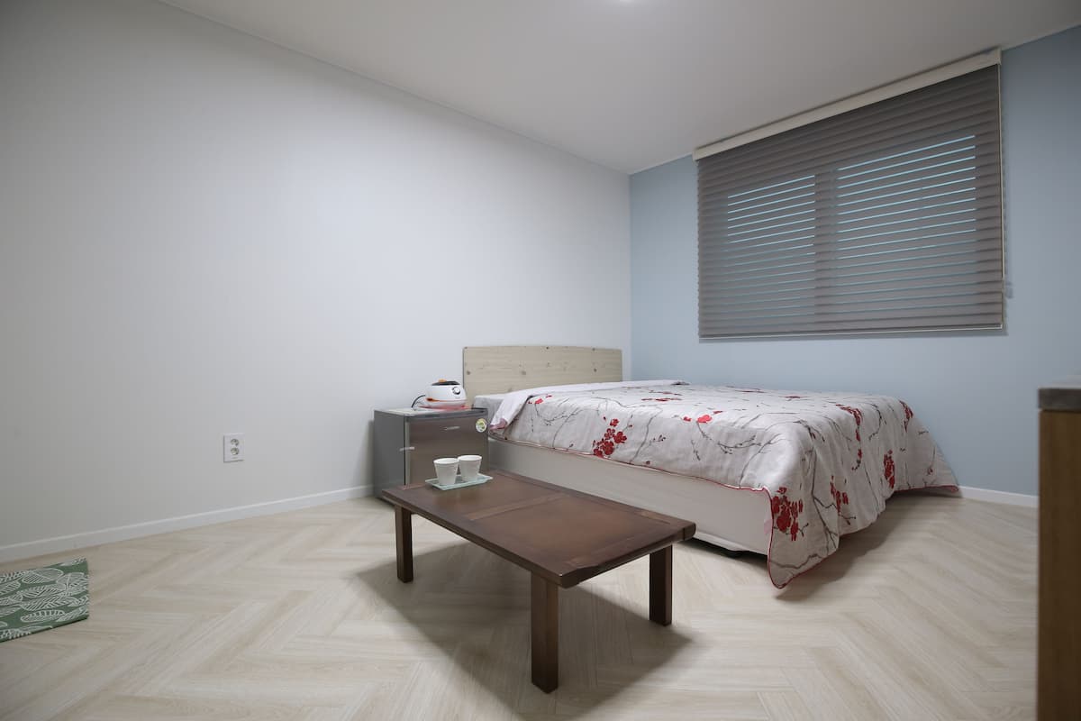 A bedroom with a bed, bedside table, and a small table with cups.