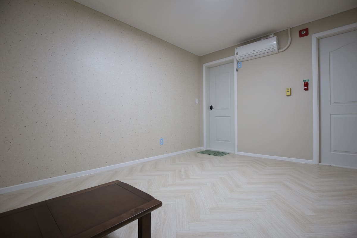 A hallway with a herringbone-patterned floor, beige walls, and a wooden bench.