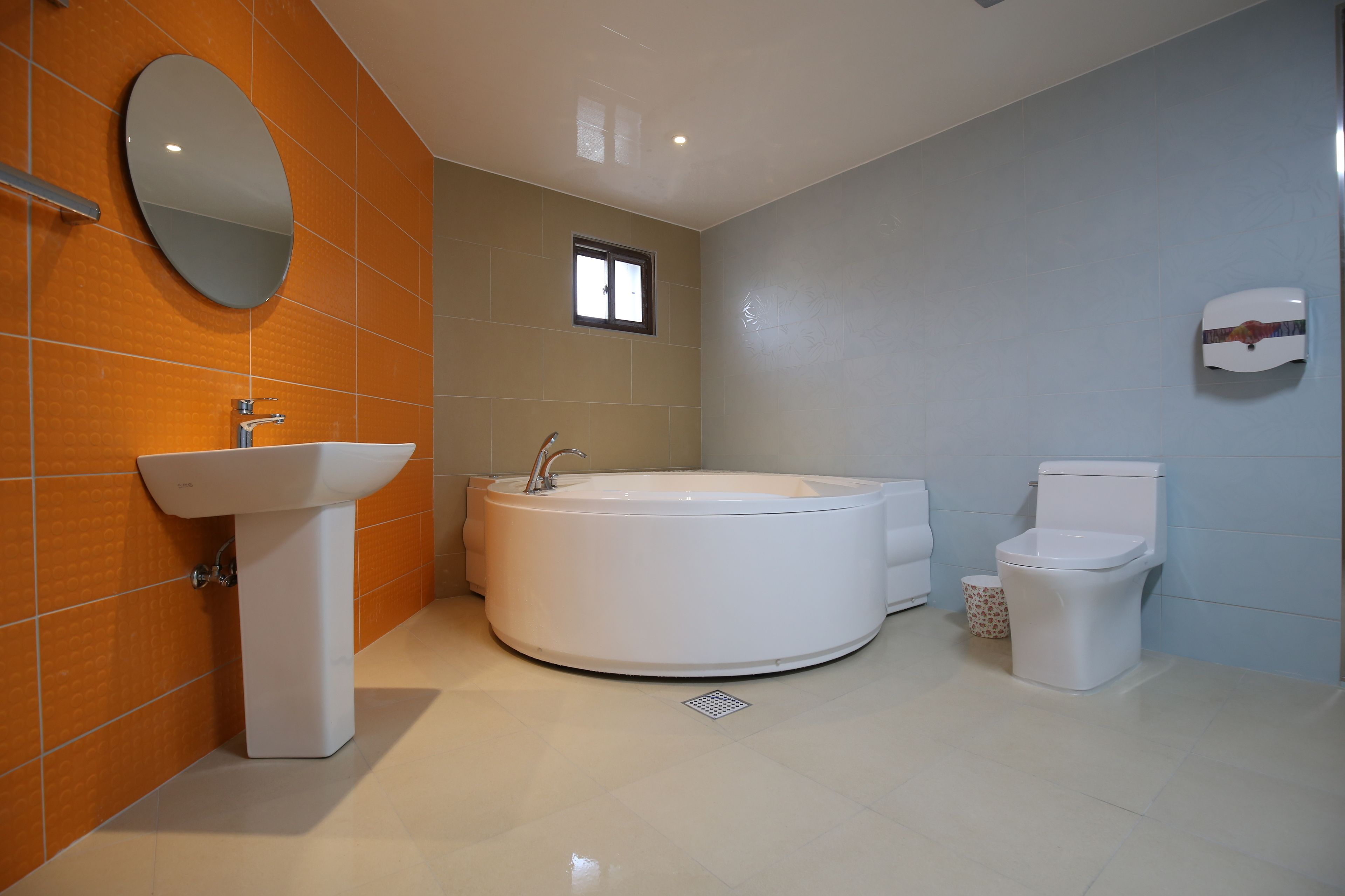 Un baño moderno con una bañera redonda, un lavamanos sobre pedestal y un inodoro.