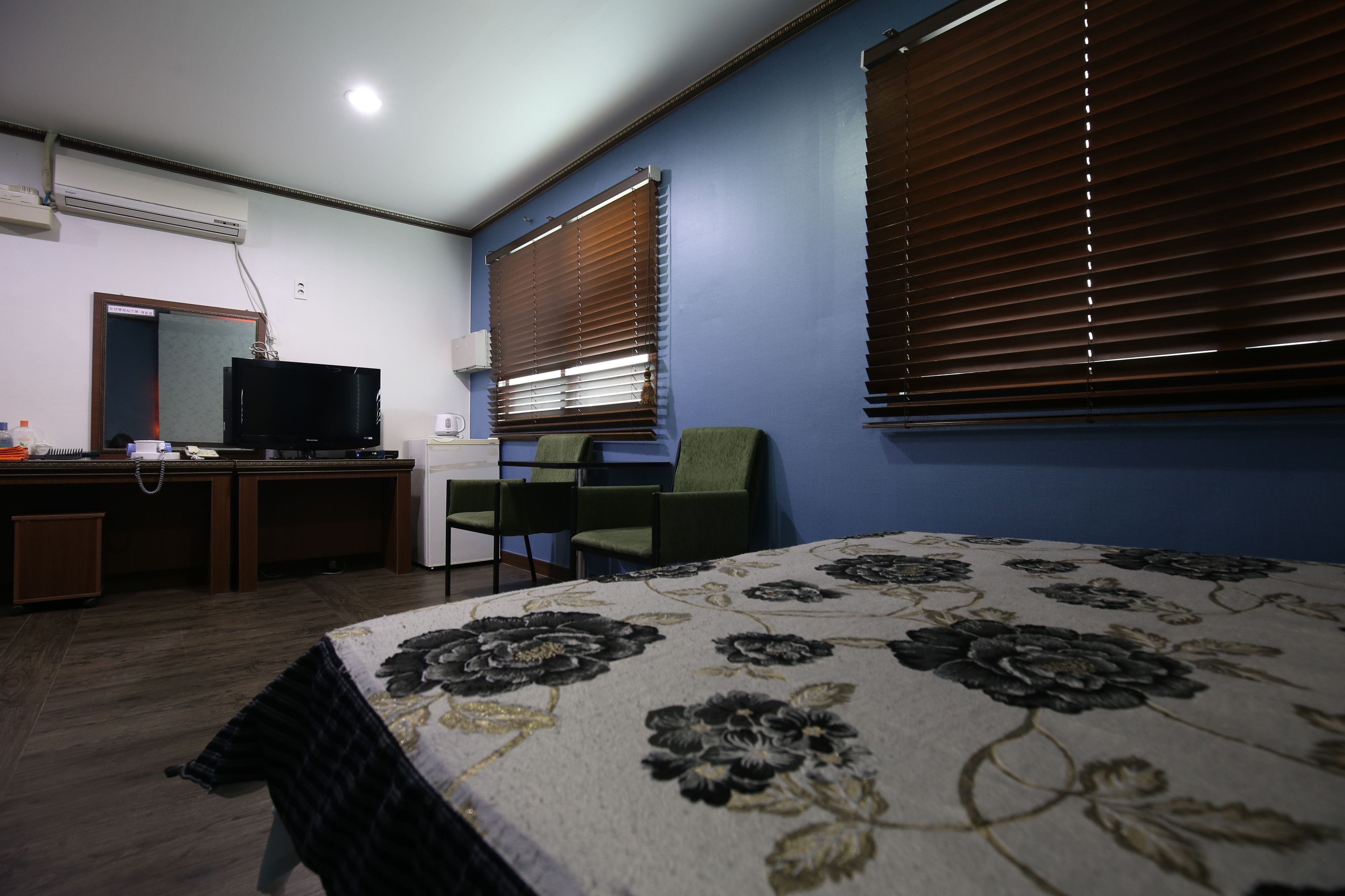 A bedroom with a bed, a desk with a computer, a chair, and a television.