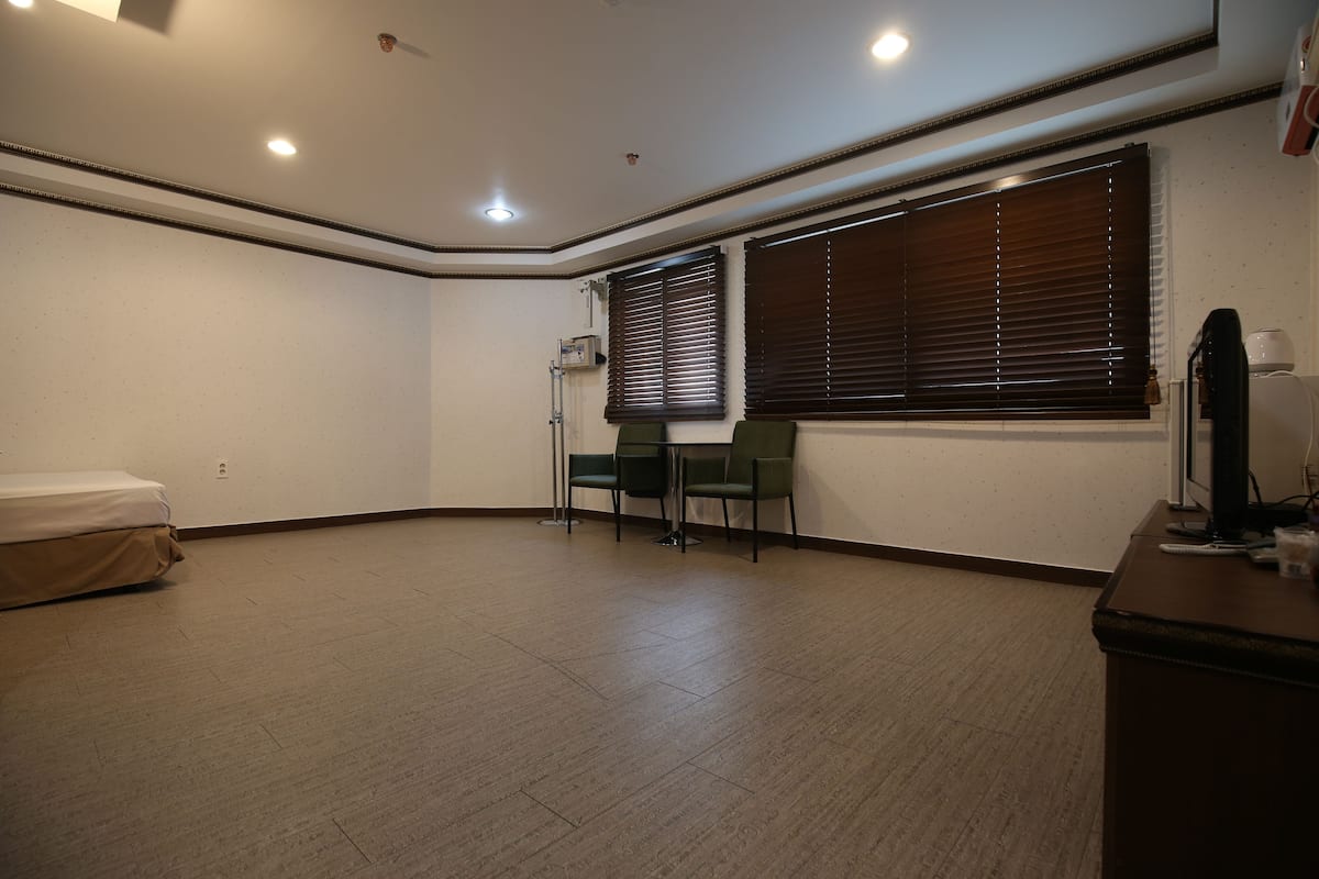 A room with a bed, a desk, a chair, and a window with blinds.