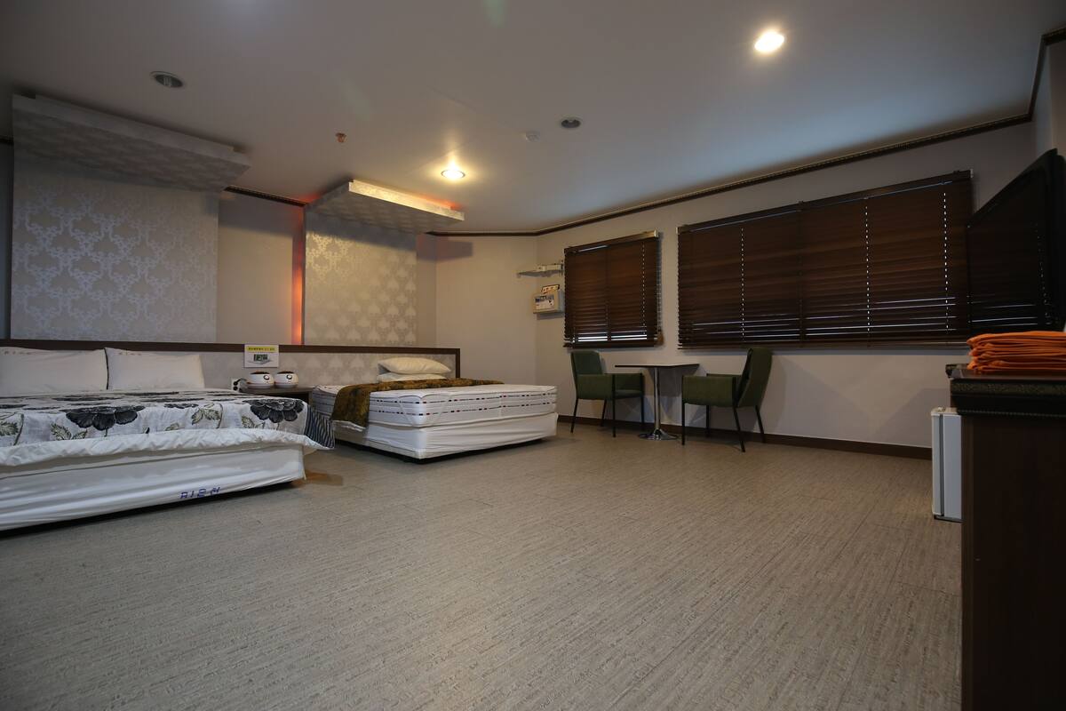 A compact hotel room with a bed, a desk, a chair, and a window.