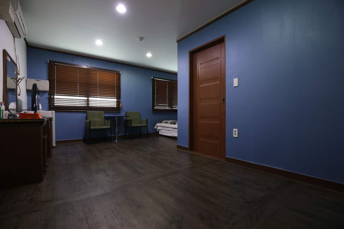 A room with blue walls, a wooden door, and a desk with a chair.