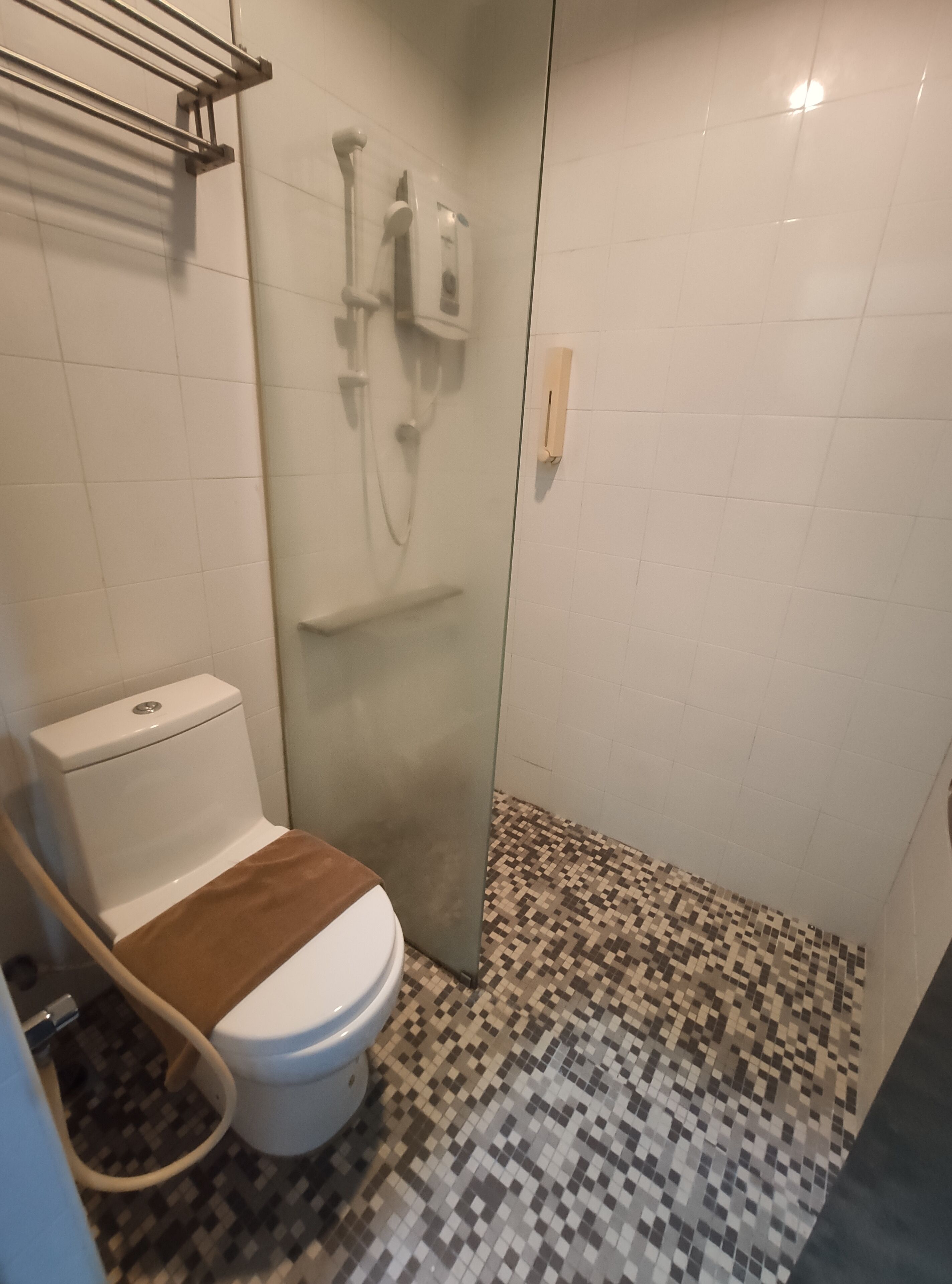 A bathroom with a toilet, a shower, and a tiled floor.