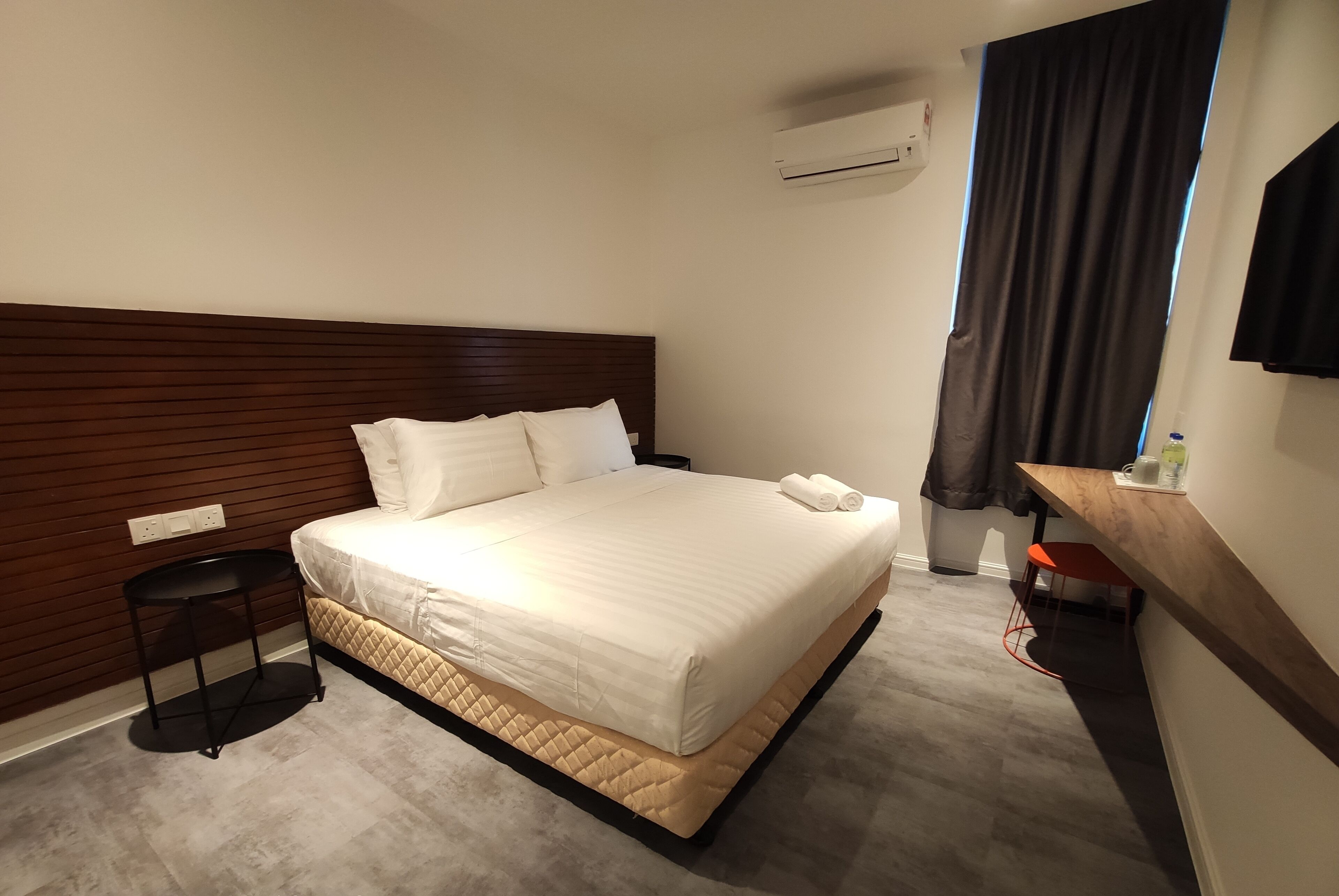 A neatly made bed with white linens, a wooden headboard, and a small bedside table with a lamp.