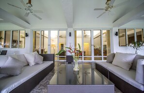 Ein modernes Wohnzimmer mit einem Glastisch, zwei Sofas und einer dekorativen Vase.