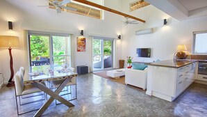 A spacious living area with a dining table, chairs, a sofa, and a kitchen area with a TV and counter.
