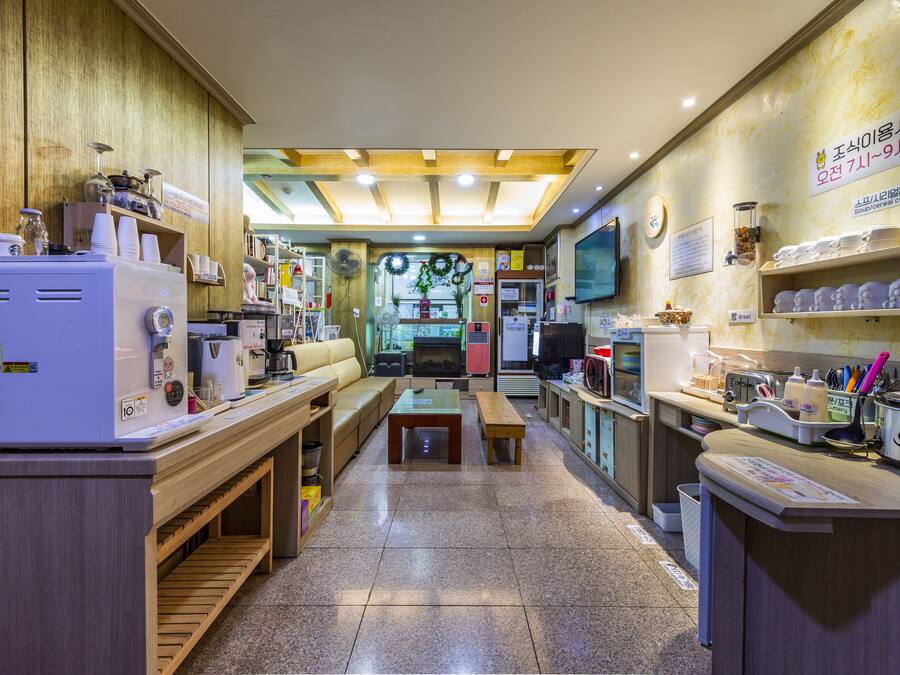 Un café acogedor con mobiliario de madera, una máquina de café y estantes con tazas y condimentos.