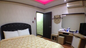 Una habitación de hotel con una cama grande, un escritorio con computadora, un televisor y un mueble pequeño.