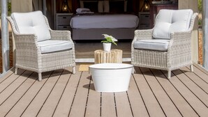 Un dormitorio al aire libre y acogedor con mobiliario de mimbre, una cama y una mesita con una planta en maceta.