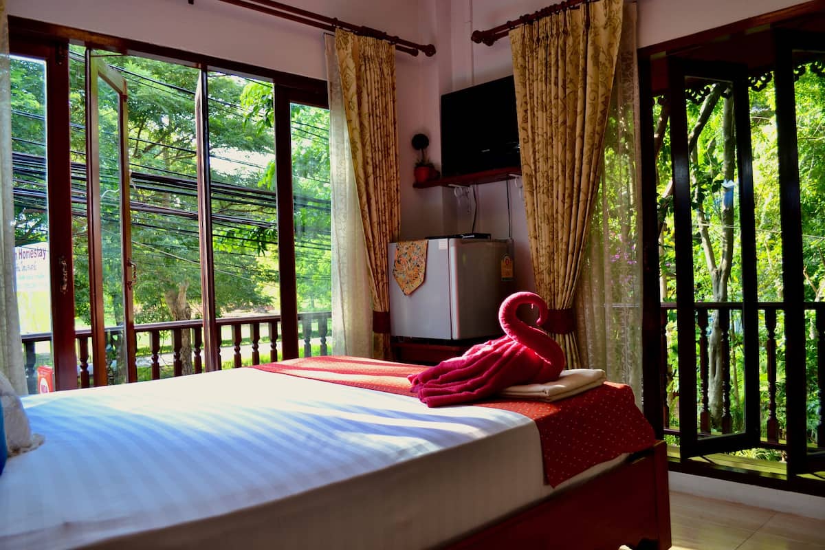Une chambre avec un lit, une télévision et une vue sur la verdure.