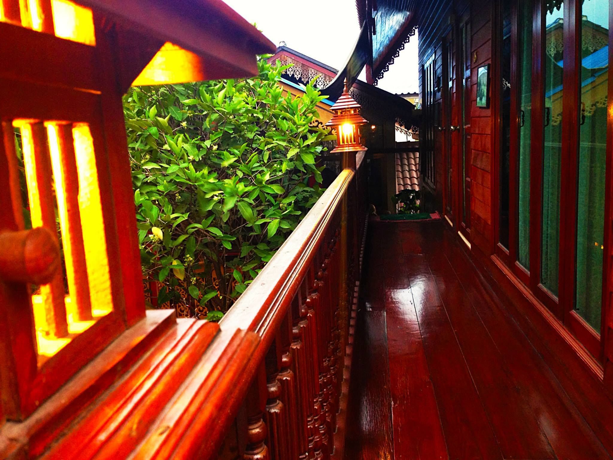 A wooden balcony with a railing, a potted plant, and a traditional lantern.