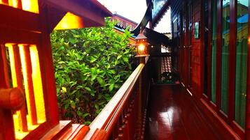 A wooden balcony with a railing, a potted plant, and a traditional lantern.