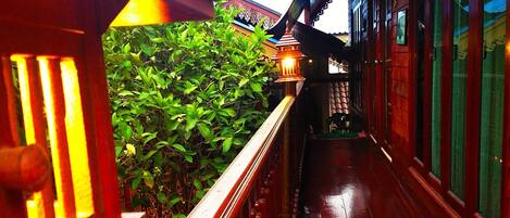 A wooden balcony with a railing, a potted plant, and a traditional lantern.