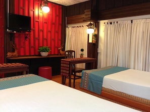 A hotel room with two beds, a desk with a chair, a television, and a red wall.