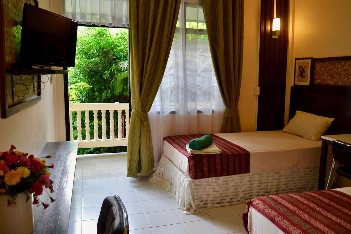 Une chambre d’hôtel avec un lit, un bureau et une chaise, une télévision et une vue sur la verdure environnante.