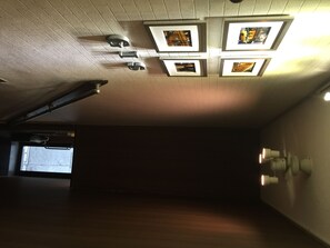 Una habitación con techo inclinado, iluminación empotrada y cuadros enmarcados.
