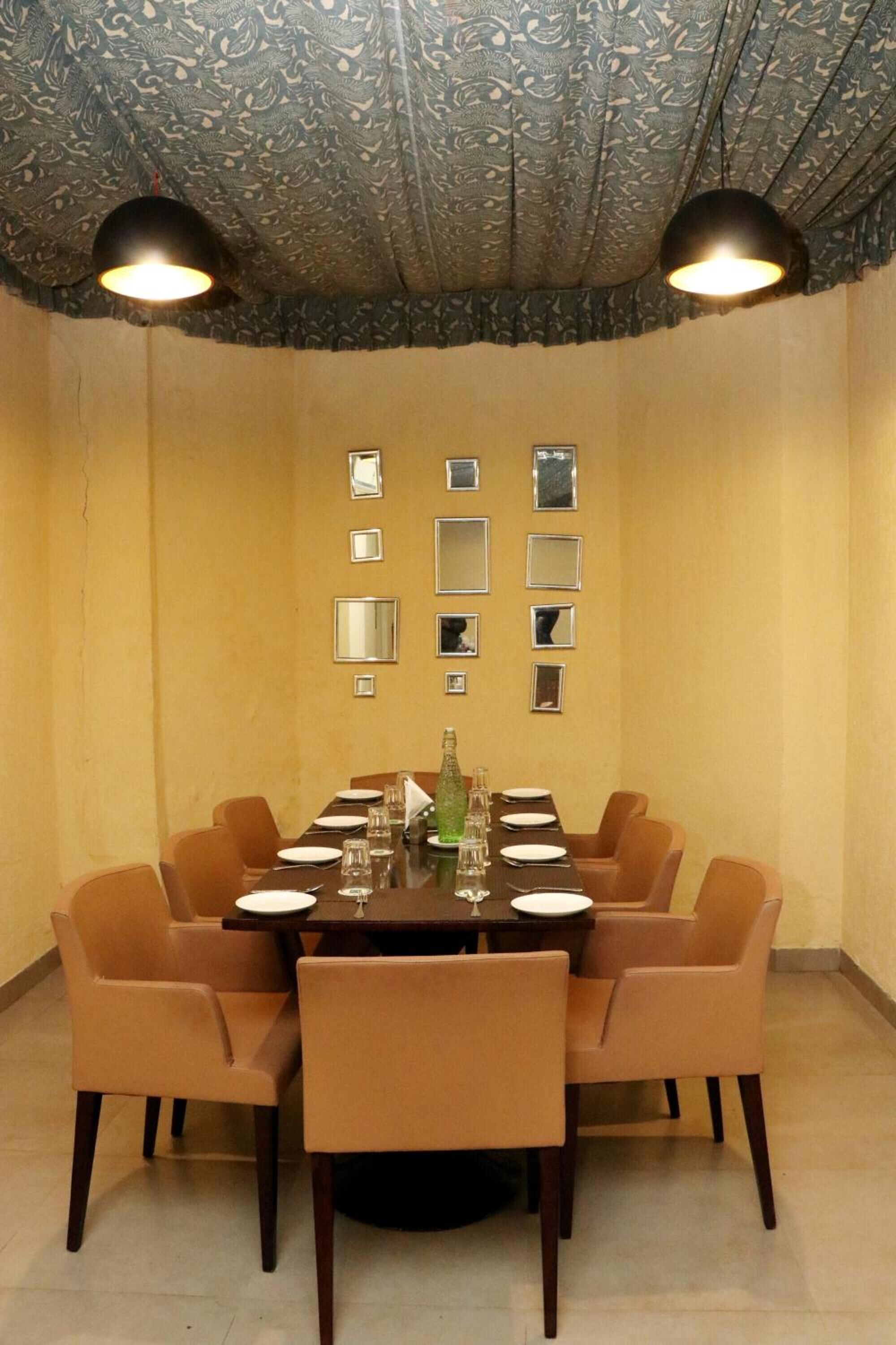 A dining room with a round table, six chairs, and two pendant lights.